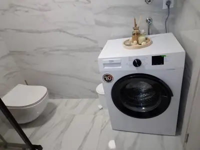 a washing machine in a bathroom with a toilet at ANDREAS lux apartman in Niš