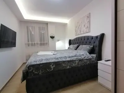 a bedroom with a large black bed in a room at ANDREAS lux apartman in Niš