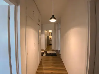 a hallway with white walls and wood floors and a light fixture at Bagi Apartmani in Raška