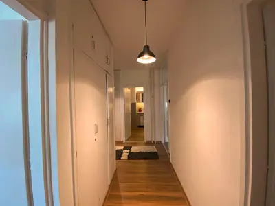 a hallway with white walls and wood floors and a light fixture at Bagi Apartmani in Raška
