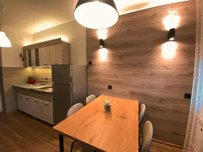 a dining room with a wooden table and a kitchen at Bagi Apartmani in Raška
