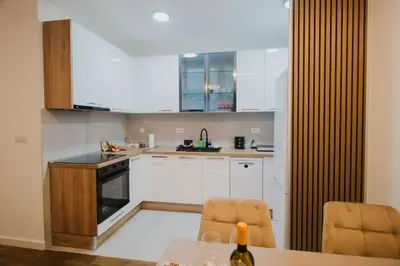 a kitchen with white cabinets and a table with two chairs at Residence Lux apartman & Spa in Niš