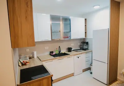 a kitchen with white cabinets and a white refrigerator at Residence Lux apartman & Spa in Niš