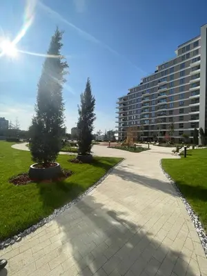 two trees in a park with a large building at Residence Lux apartman & Spa in Niš