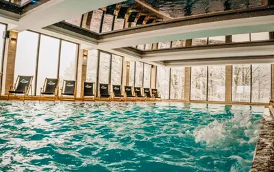 a pool of water with chairs in a building at Gold Apartments Kopaonik in Kopaonik