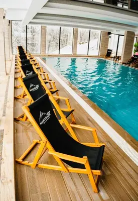 a row of lounge chairs next to a swimming pool at Gold Apartments Kopaonik in Kopaonik