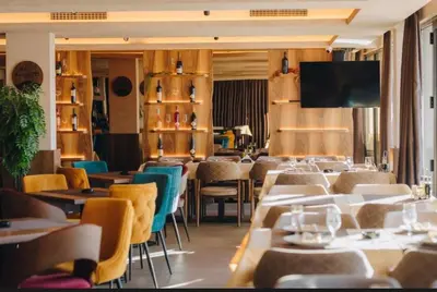a restaurant with tables and chairs and a flat screen tv at Gold Apartments Kopaonik in Kopaonik