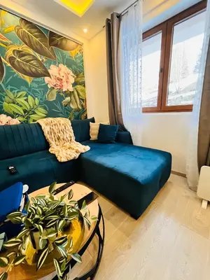 a living room with a blue couch and a table at Gold Apartments Kopaonik in Kopaonik
