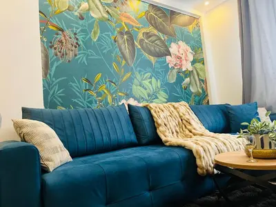 a blue couch in a living room with a floral wallpaper at Gold Apartments Kopaonik in Kopaonik