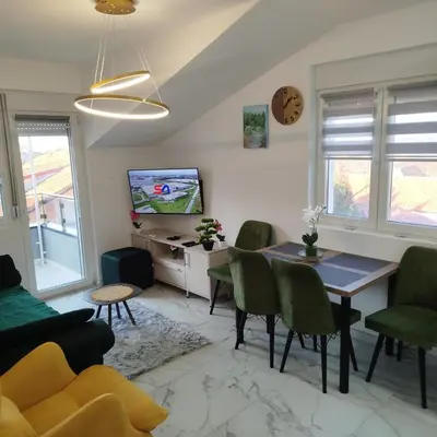a living room with a table and chairs and a tv at Cera maximus apartment in Soko Banja