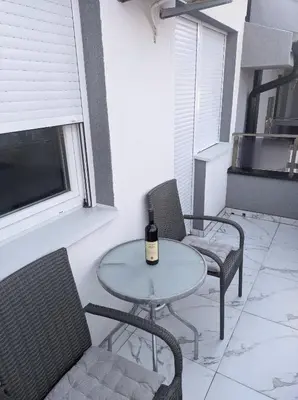 a table and chairs with a bottle of wine on it at Cera maximus apartment in Soko Banja