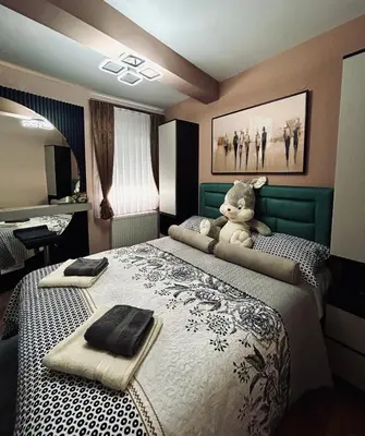 a bedroom with a teddy bear sitting on a bed at KARENJINA Apartmani in Vranje