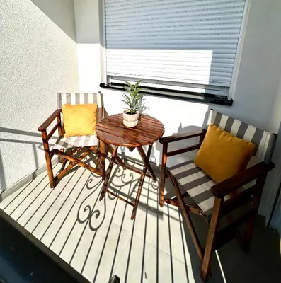 a balcony with two chairs and a table and a plant at KARENJINA Apartmani in Vranje