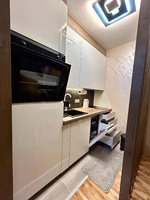a kitchen with white cabinets and a black microwave at KARENJINA Apartmani in Vranje