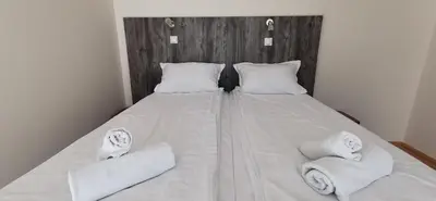 a white bed with two pillows and towels on it at Villa MILSA Half Board & Pool in Soko Banja