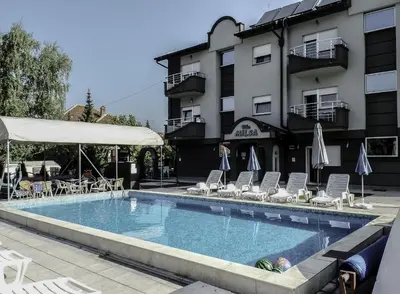 a swimming pool with chairs and umbrellas next to a building at Villa MILSA Half Board & Pool in Soko Banja
