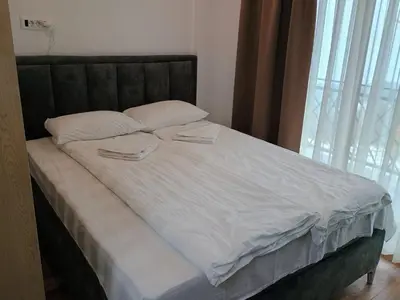 a bed with white sheets and two towels on it at Apartman Simona President Kop in Kopaonik