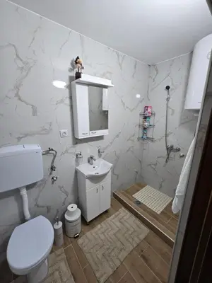 a white bathroom with a toilet and a sink at Apartman Kocić in Temska