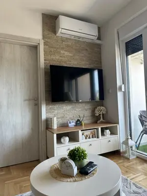 a living room with a white table and a tv at Dorin Kutak in Vrnjačka Banja