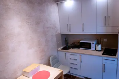 a kitchen with white cabinets and a table and a microwave at Lux Studio Kraljevi Čardaci in Kopaonik