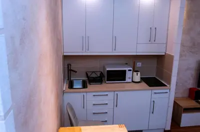 a small kitchen with white cabinets and a microwave at Lux Studio Kraljevi Čardaci in Kopaonik