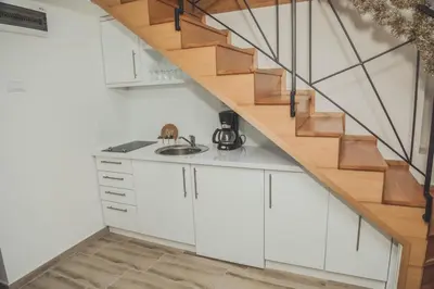 a kitchen with white cabinets and a wooden staircase at Luna-L in Vrnjačka Banja