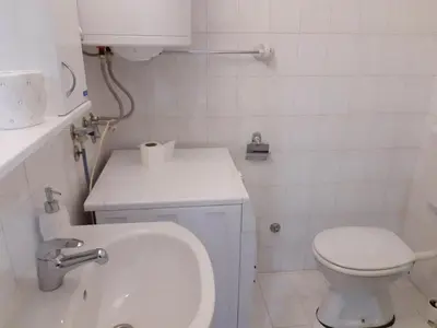 a white bathroom with a toilet and a sink at Luna-L in Vrnjačka Banja