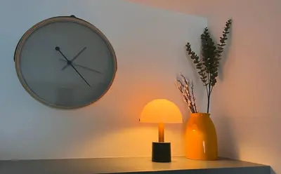a table with a lamp and a clock and a vase at Apartman A4 in Vrnjačka Banja