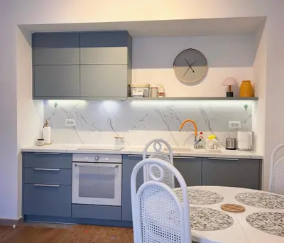 a kitchen with blue cabinets and a table and a clock at Apartman A4 in Vrnjačka Banja
