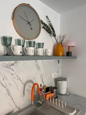 a clock on a shelf above a kitchen sink at Apartman A4 in Vrnjačka Banja