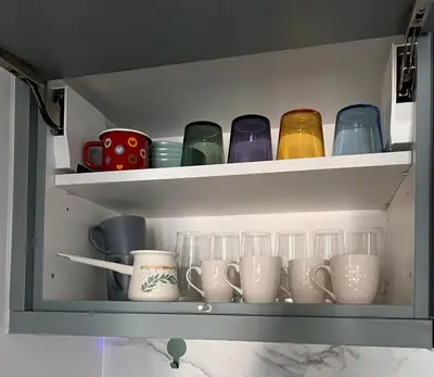 a shelf with cups and mugs on it at Apartman A4 in Vrnjačka Banja