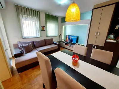 a living room with a couch and a table with chairs at Apartman Maslačak Vrnjačka Banja in Vrnjačka Banja