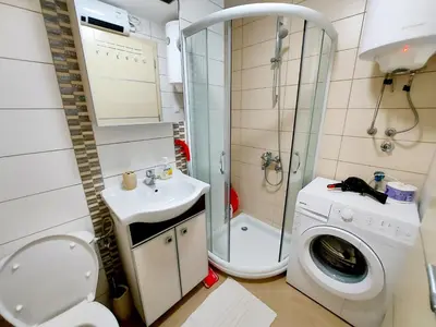 a bathroom with a toilet and a sink and a washing machine at Apartman Maslačak Vrnjačka Banja in Vrnjačka Banja