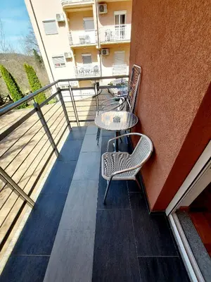 a balcony with two tables and chairs on a building at Apartman Maslačak Vrnjačka Banja in Vrnjačka Banja