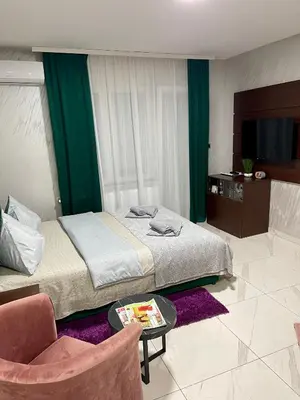 a bedroom with a bed and a chair and a table at Pink Apartmani in Jagodina