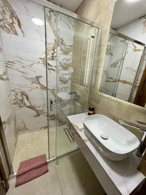a bathroom with a sink and a glass shower at Pink Apartmani in Jagodina