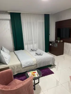 a bedroom with a bed and a chair and a table at Pink Apartmani in Jagodina