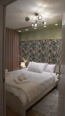 a bedroom with a large white bed with a floral wall at Astera 1 in Vrnjci