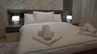 a white bed with towels on it with two lamps at Astera 2 in Vrnjci