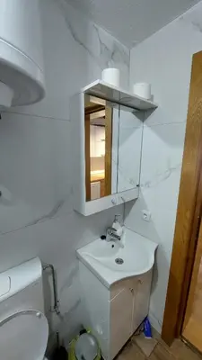 a white bathroom with a sink and a toilet at Apartman Mećavnik Kopaonik in Kopaonik