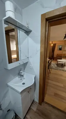 a white bathroom with a sink and a mirror at Apartman Mećavnik Kopaonik in Kopaonik