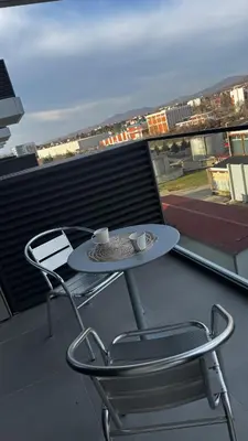 a table and chair on a balcony with a view at Planet A in Niš