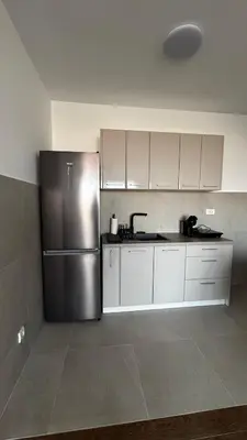 a kitchen with a stainless steel refrigerator and white cabinets at Planet A in Niš