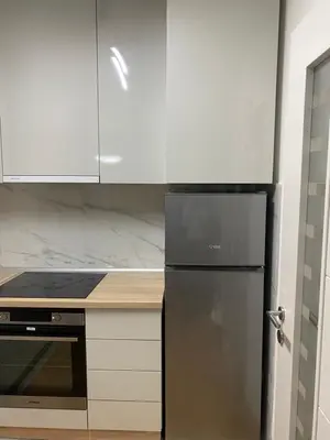 a kitchen with a black refrigerator and white cabinets at Apartmani Ivanović in Vrnjačka Banja