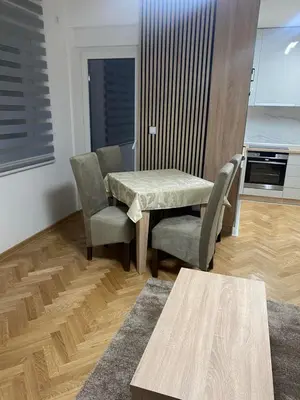 a living room with a table and chairs and a kitchen at Apartmani Ivanović in Vrnjačka Banja