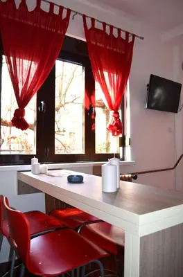 a room with red curtains and a desk with red chairs at Apartmants Night Lux in Niš
