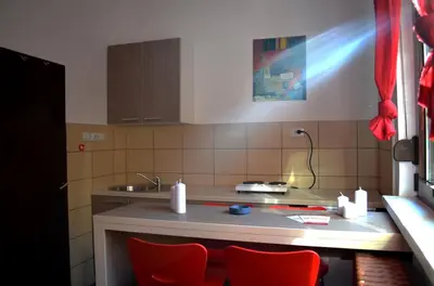 a kitchen with two red chairs and a counter at Apartmants Night Lux in Niš
