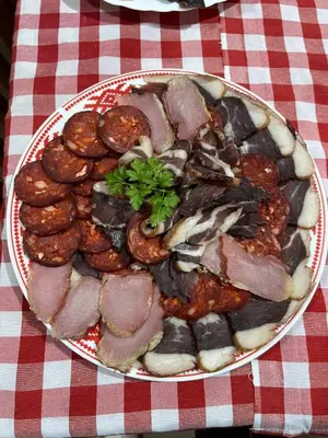a plate of food with meat and mushrooms on a table at Ribnjak Filopivic in Pleš
