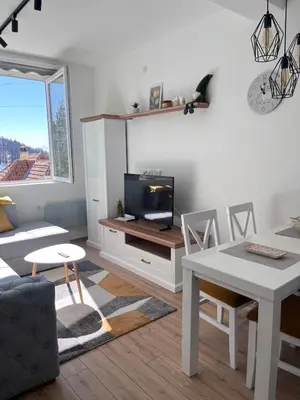 a living room with a table and a tv at KopStar Apartment Kopaonik 19 in Kopaonik