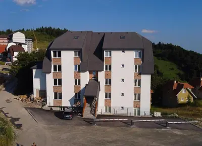 a large white building with a black roof at KopStar Apartment Kopaonik 19 in Kopaonik